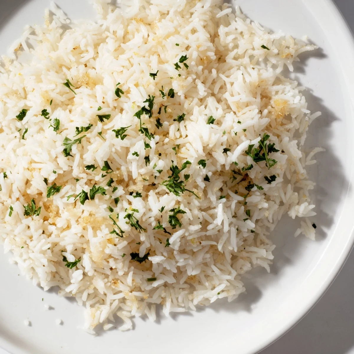 Steaming hot garlic butter rice, fluffy and studded with garlic, ready to serve alongside dinner.