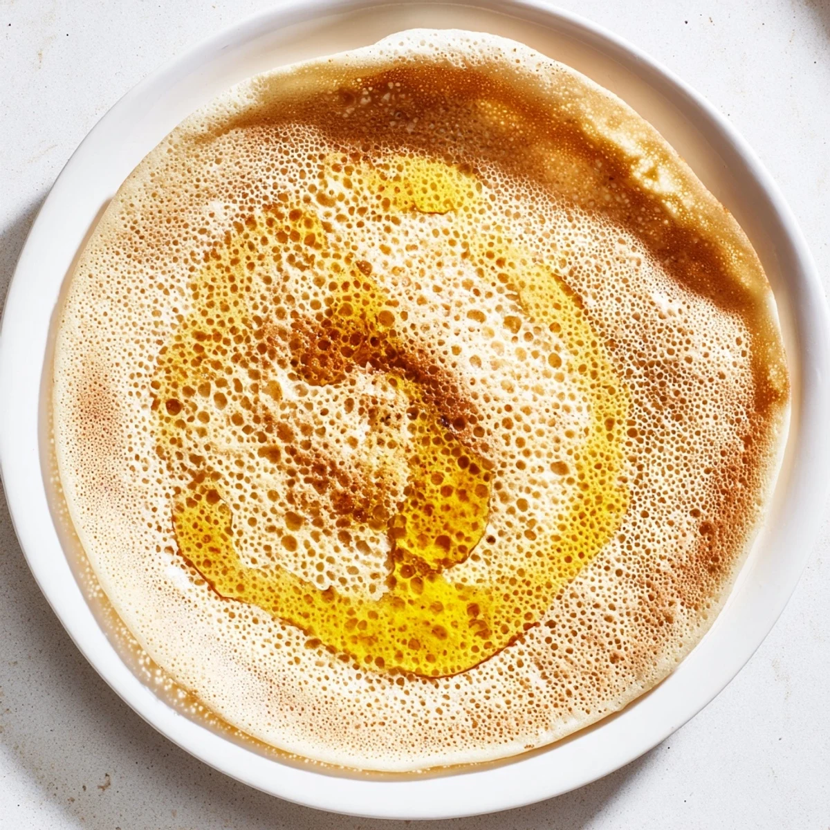 Warm and spongy Moroccan Baghrir crumpets, perfect for breakfast, served with a delicious honey-butter drizzle.