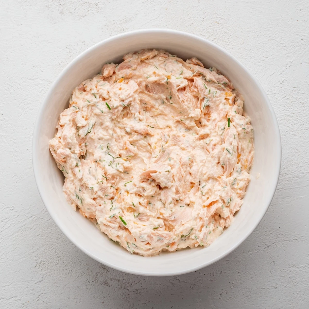 A creamy smoked salmon dip served in a rustic bowl, garnished with fresh dill, chives, and lemon wedges for a bright, tangy flavor.