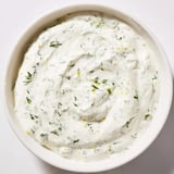 A bowl of tangy Greek Yogurt Herb Dip, garnished with lemon zest, perfect for spreading on sandwiches or dipping veggies.  