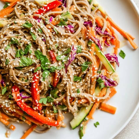 A vibrant bowl of soba noodle salad with visible colorful veggies and sesame seeds.
