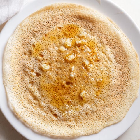 Close-up shot shows light, airy Moroccan Baghrir pancakes, ready to be soaked in butter and sweet honey.