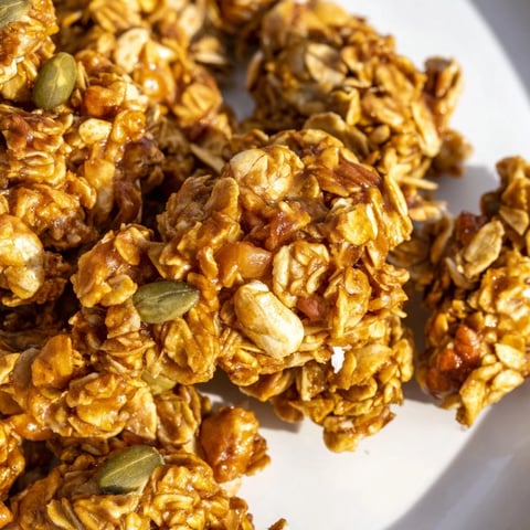 Golden brown Granola Clusters Homemade glistening with honey and coconut, served in a ceramic bowl with fresh berries and yogurt.