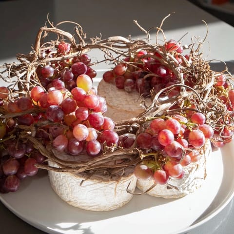 The Rustic Vineyard offers a delightful cheese presentation with ripe grapes draped over the artisan cheese.