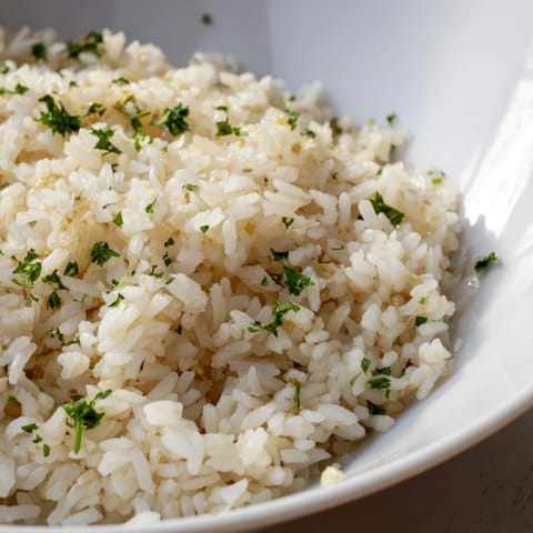 Beautiful close-up of fragrant garlic butter rice, featuring glistening grains absorbing savory broth in a bowl.