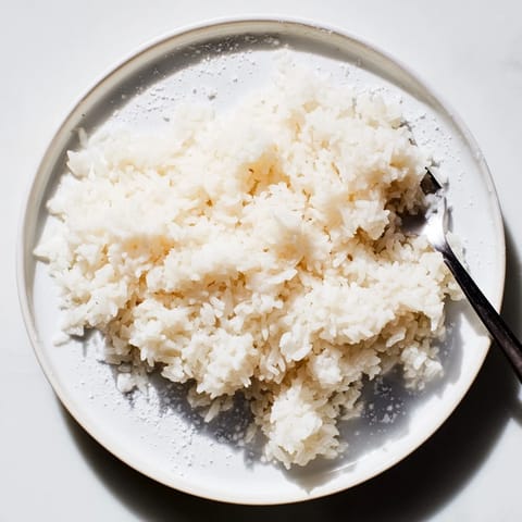 Aromatic Coconut Jasmine Rice steams gently, appearing light and fluffy, an ideal side dish.