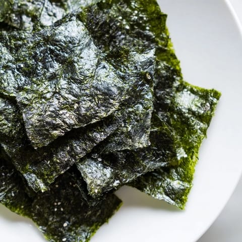 Two stacked nori sheets cut into squares, roasted to a crisp and ready to serve with rice bowls.