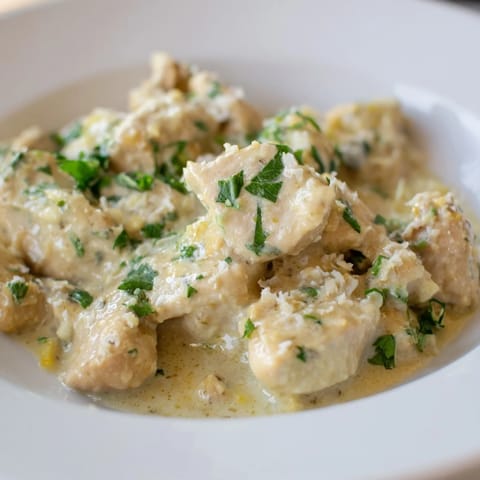 Tender Creamy Garlic Chicken Bites plated beside fluffy mashed potatoes, with garlic sauce pooled at the base.
