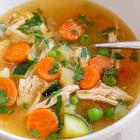 A comforting bowl of Spring Garden Chicken Soup featuring tender zucchini, fresh parsley, and a bright squeeze of lemon.  