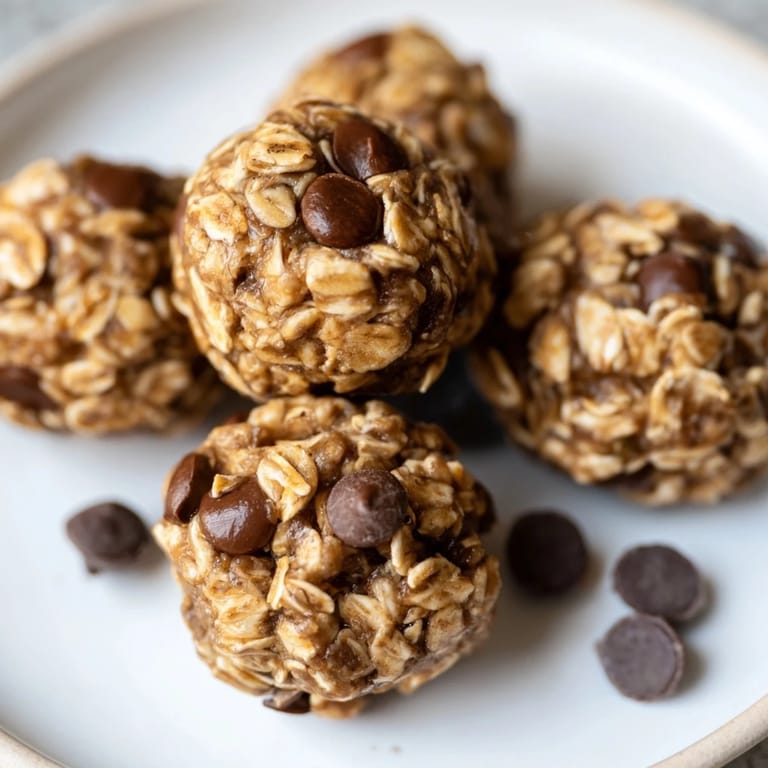 A close-up of perfectly round no-bake peanut butter energy balls with visible oats and mini chocolate chips.