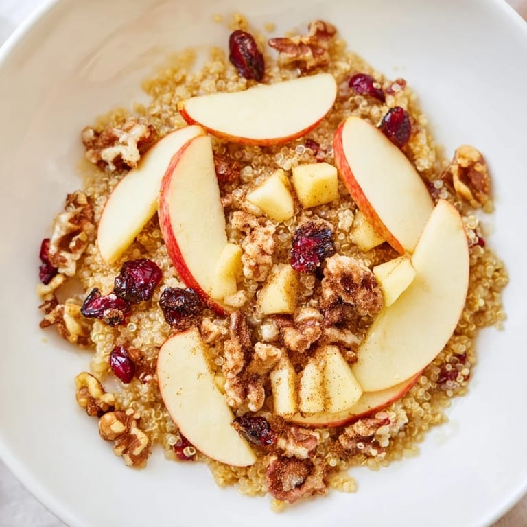 Delicious, warm Apple Cinnamon Quinoa Bowl recipe, a comforting vegetarian breakfast with fresh apple slices.