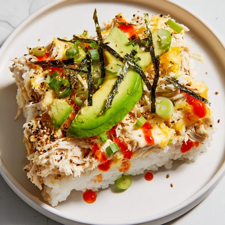 A warm, golden-brown Chicken Sushi Bake, perfect for sharing, topped with avocado slices and sesame seeds.