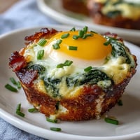 Fluffy green eggs and ham baked in muffin cups with melted cheddar cheese and spinach.
